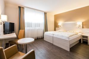 a hotel room with a bed and a tv at Land-gut-Hotel Westerkrug in Wanderup