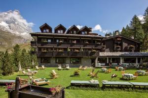 a large building with chairs and tables in front of it at Hotel Hermitage Relais & Châteaux in Breuil-Cervinia