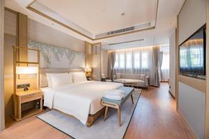 a bedroom with a large white bed and a couch at Atour S Hotel SHanghai Baoshan Gucun Park in Shanghai