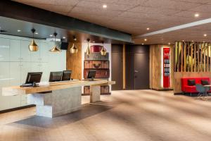 un hall de bureau avec une réception et des chaises dans l'établissement ibis Saint Quentin en Yvelines - Vélodrome, à Montigny-le-Bretonneux