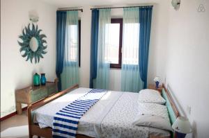 パラーウにあるLoft Palauのベッドルーム1室(青いカーテンと鏡付きのベッド1台付)
