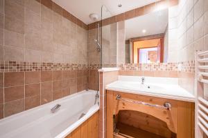 ein Badezimmer mit Badewanne, Waschbecken und Spiegel in der Unterkunft Le Chalet - C204 - Vue Montagne in Le Corbier + 12 Fotos