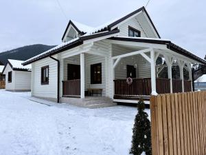 a white house with a porch in the snow at Котедж Маєток Ярини in Krivopolʼye