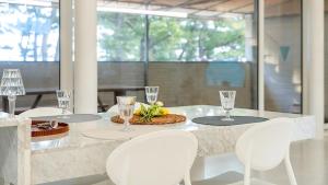 einen Esstisch mit weißen Stühlen und Gläsern darauf in der Unterkunft Samcheok Migaloo Pool Villa Pension in Samcheok