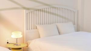 ein weißes Schlafzimmer mit einem weißen Bett und einer Lampe in der Unterkunft Samcheok Migaloo Pool Villa Pension in Samcheok