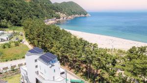 ein weißes Haus mit Solarpaneelen an einem Strand in der Unterkunft Samcheok Migaloo Pool Villa Pension in Samcheok
