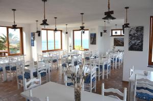 ein Esszimmer mit weißen Tischen und Stühlen und Fenstern in der Unterkunft Hotel Punta Barone in Santa Marina Salina