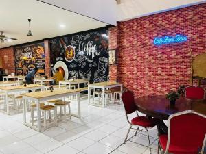 a restaurant with tables and chairs and a brick wall at Hotel Huswah Airport in Jakarta