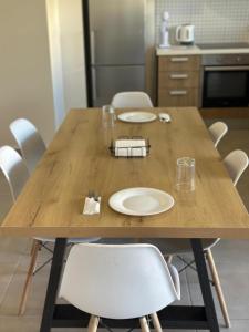 a wooden table with white plates and chairs in a kitchen at Two Bedrooms Apartment with Private Balcony in Yukarı Lakatamya