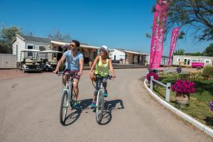 a man and woman riding bikes down a road at Camping Officiel Siblu Le Lac des Rêves in Lattes