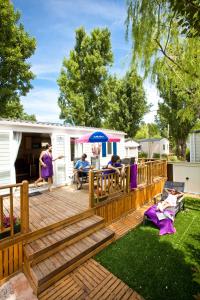 a wooden deck with people sitting on it at Camping Officiel Siblu Le Lac des Rêves in Lattes