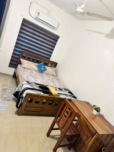 een slaapkamer met een bed en een houten tafel bij White coral beach home in Alleppey