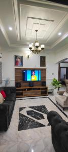 Una sala de estar con televisión y un sofá. en Beautiful 2 beds with self compound and private parking space, en Iju Junction
