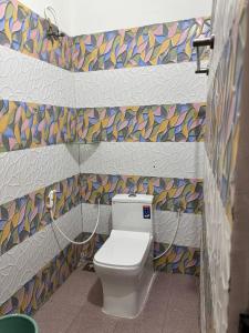 een badkamer met een toilet met een kleurrijke mozaïekmuur bij White coral beach home in Alleppey