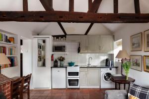 een keuken met witte apparatuur en een bakstenen vloer bij The Cottage in Fernhurst