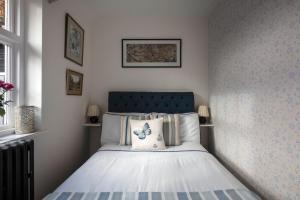 een slaapkamer met een bed met een blauw hoofdeinde bij The Cottage in Fernhurst