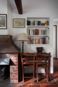 een kamer met twee stoelen, een tafel en een boekenplank bij The Cottage in Fernhurst