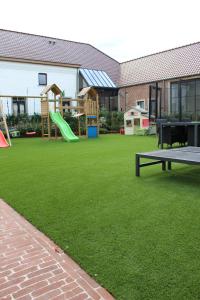 ズワールムにあるHof van Vlaanderenのテーブルと滑り台のある遊び場のある庭