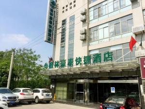 a building with cars parked in front of it at GreenTree Inn Yancheng Economic Development Zone Management Committee Express Hotel in Ti-pa-yung