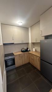 una cucina con mobili bianchi e un frigorifero nero di Sky View - stan na dan Banja Luka a Banja Luka