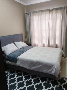 een slaapkamer met een bed met een raam en een tapijt bij Two Lilies in Vosburg