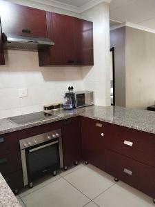 een keuken met bruine kasten en een kookplaat oven bij Two Lilies in Vosburg