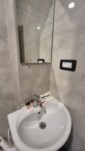 Un lavabo blanco en un baño con espejo. en Hotel City Palace, en Bhagalpur