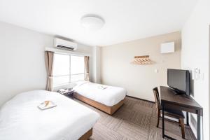 a hotel room with two beds and a desk with a television at Best Hotel in Tokyo