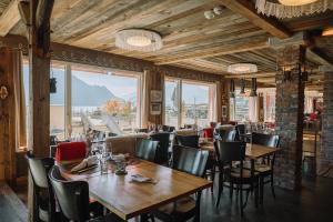a restaurant with wooden tables and chairs and windows at Alpenblick Weggis - Panorama & Alpen Chic Hotel in Weggis