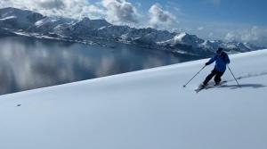 Una persona está esquiando por una pendiente cubierta de nieve. en Bleik Sea Cabins, en Bleik
