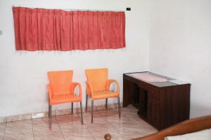 two orange chairs and a desk in a room at Nirina Homestay Pringsewu Mitra RedDoorz in Margakaya