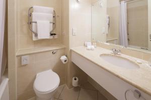 a bathroom with a toilet, sink, and mirror at Pomme d'Or Hotel in Saint Helier Jersey