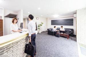 un grupo de personas sentadas en un mostrador en una habitación en Best Hotel en Tokio