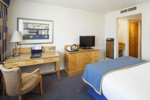 a hotel room with a bed, desk and television at Pomme d'Or Hotel in Saint Helier Jersey