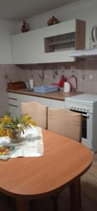 eine Küche mit einem Holztisch mit Stühlen und einem Herd in der Unterkunft Apartment Lile in Kučište