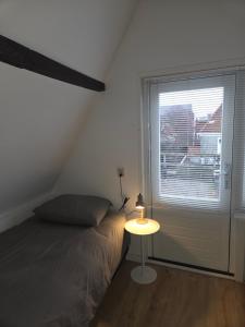 a bedroom with a bed and a table with a window at Slapen bij De Buren in Alkmaar