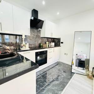 una cucina con mobili bianchi e ripiani neri di Cozy Escape Garden Flat a Birmingham Altre 10 foto