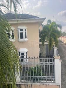 een wit huis met een hek en een palmboom bij Homegate Marina Waterview Apartment in Araromi