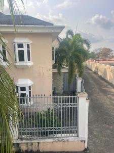 een wit huis met een hek en een palmboom bij Homegate Marina Waterview Apartment in Araromi +1 foto