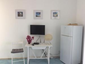 a kitchen with a white refrigerator and a table and a desk at La Nacatola in Lipari