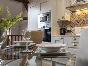 een eetkamer met een glazen tafel en een keuken bij Blists Hill Cottage Near Ironbridge Victorian Museum in Telford