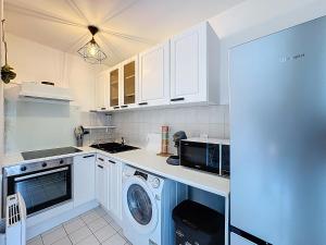 een keuken met witte kasten en een wasmachine en droger bij Studio Moderne avec jardin et garage in Nanterre
