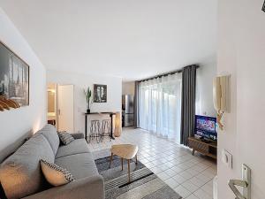 een woonkamer met een bank en een tv bij Studio Moderne avec jardin et garage in Nanterre