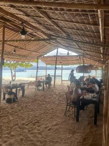 Un grupo de personas sentadas en mesas en la playa. en Bice Camp Darocotan, en El Nido