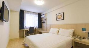 a hotel room with a white bed and a desk at Jinjiang Inn Weihai Liugong Island Scenic Spot Shopping Market in Weihai