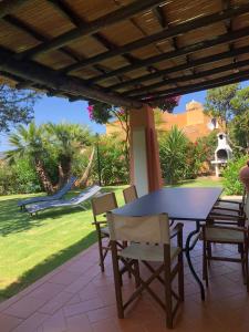 a patio with a table and chairs and a hammock at Appartamento Stintino in Cuile Pazzoni