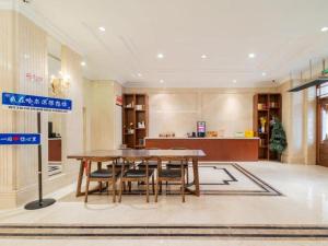 Vienna Hotel Harbin Central Avenue في هاربين: غرفة طعام بها طاولة وكراسي