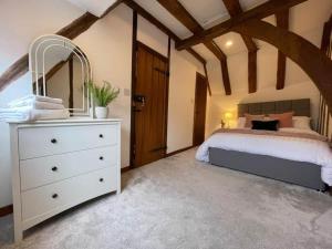 Un dormitorio con una cama y una cómoda con espejo. en Rural Country Suites - Judge's Lodge, en East Grinstead