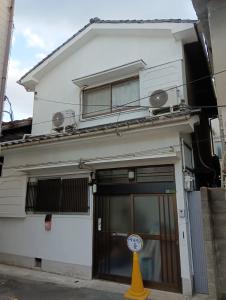 ein Gebäude mit einer Uhr davor in der Unterkunft marusan houseマルさんの家 in Osaka