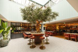 a tree in the middle of a restaurant with a table and chairs at Mount Errigal Hotel, Conference & Leisure Centre in Letterkenny